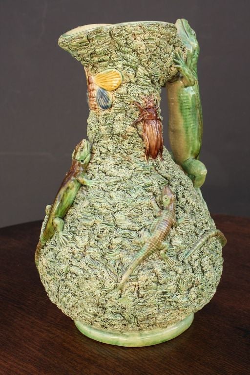 A lovely 19th c. Majolica Palissy ewer and cover featuring a large lizard handle, one further lizard, two beetles, two salamanders, and a moth or butterfly. All on a green mossy ground with cream interior and underside. Cover with a frog forming the