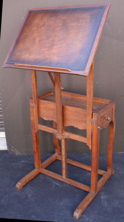 An Arts and Crafts-era easel and drawing table by the celebrated London art suppliers, Lechertier Barbe. <br />
Featuring an adjustable easel with embossed leather surface, attached to a small desk table with pull-out drawer, with hinged top that