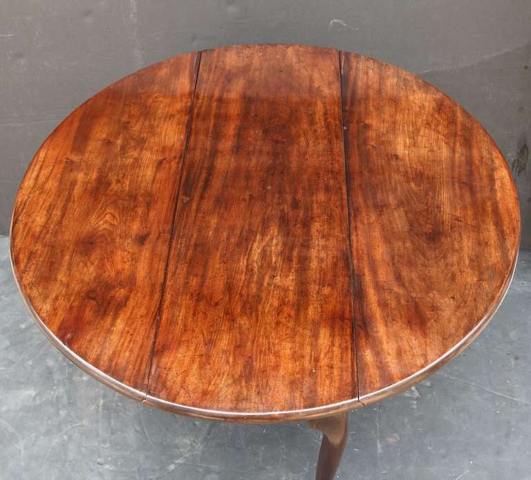 A handsome English drop-leaf table of fine Cuban mahogany from the George II period, featuring nicely-crafted demilune sides that fold up onto retractable cabriole legs to make a round or circular surface for dining or serving. Set upon pad