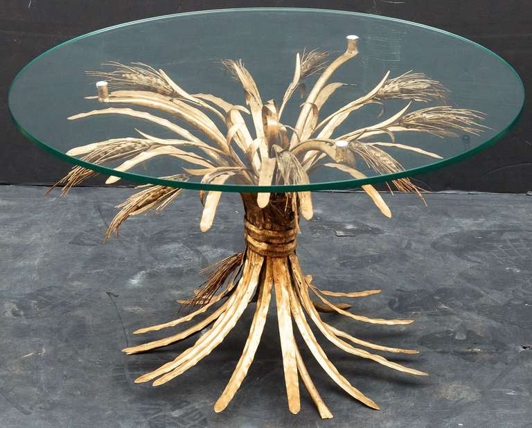 An Italian cocktail or coffee table (or low table) featuring a round glass top set upon a beautifully-designed and constructed sheaf of wheat base with original gilt finish. Perfect for use as an end or side table.

Coco Chanel had a similar piece