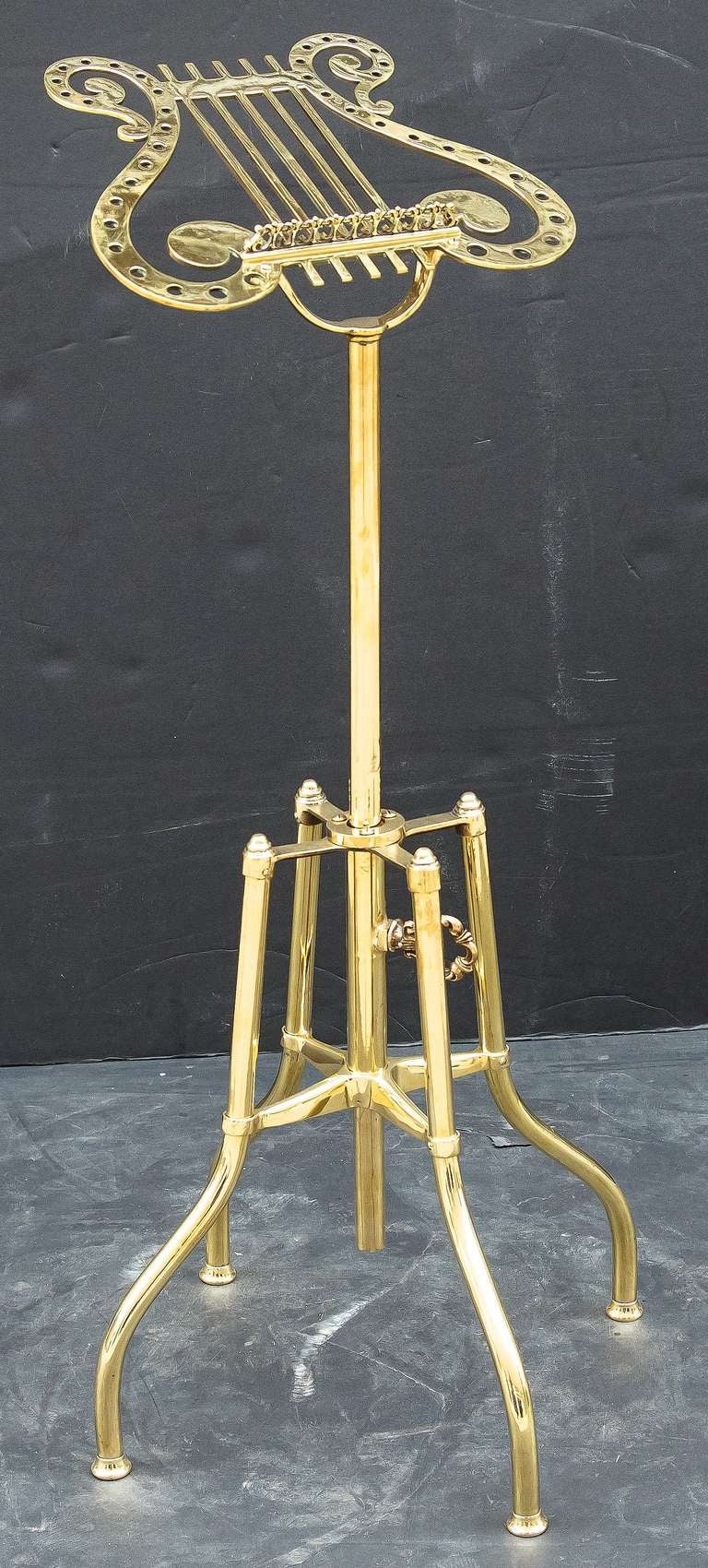 A handsome English music stand of brass featuring a lyre-shaped folio easel mounted to a four-legged stand, allowing for adjustable height of between 33.5 (down) to 43