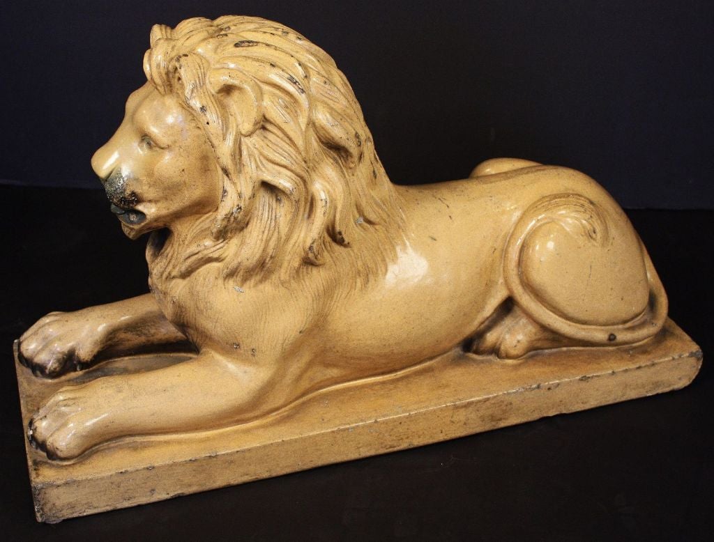 A large English lion figurine of glazed stoneware featuring a recumbent lion with fine modelling to the head and body.

Dimensions: H 18 1/2