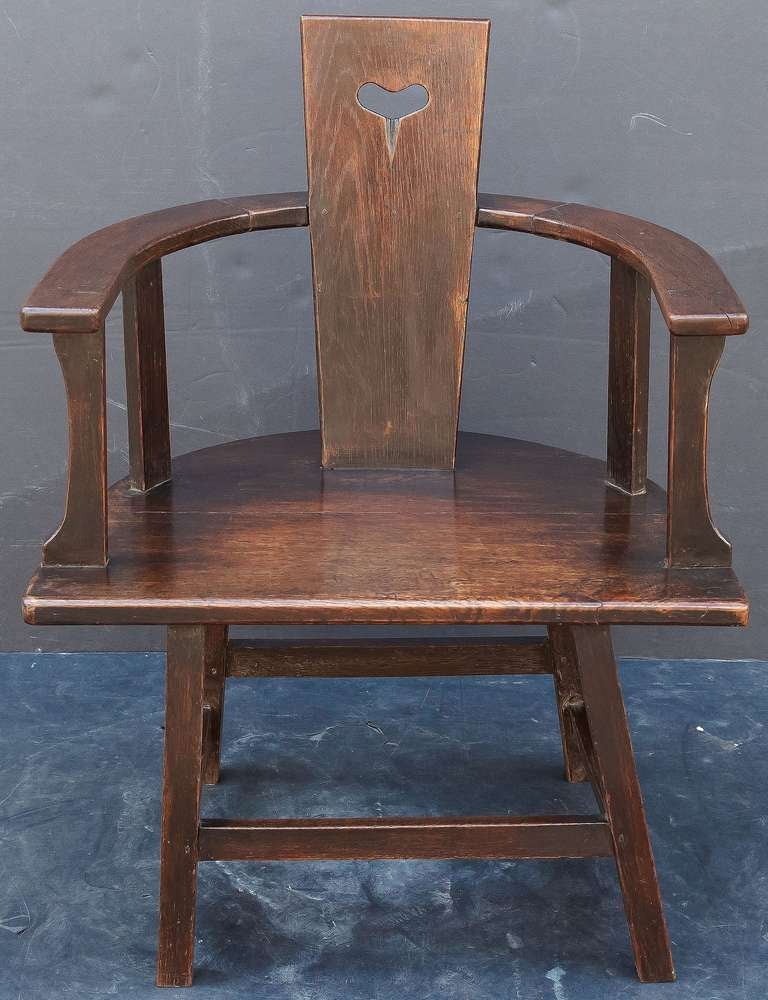 A handsome English armchair from the Arts and Crafts period, featuring a slat back with heart cutaway, joined to a barrel shaped arm and seat, on stretcher base.