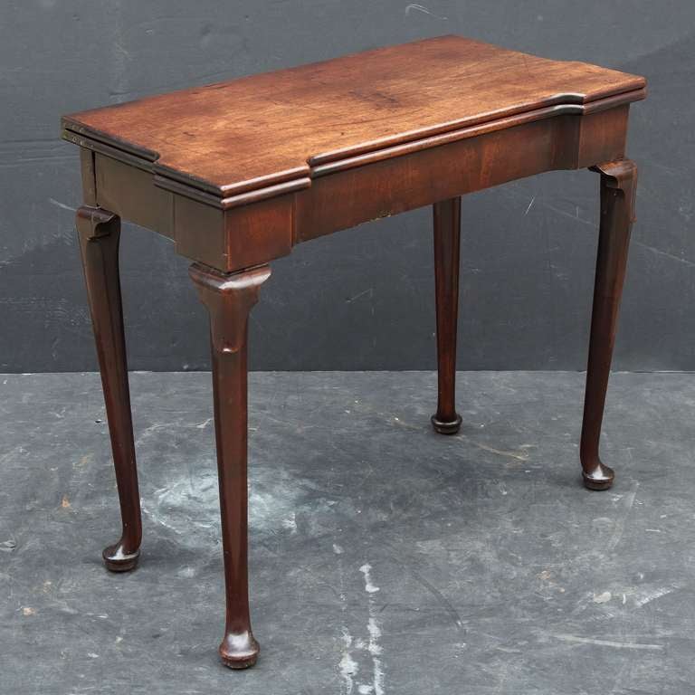 A handsome English folding tea table from the George II period of mahogany, featuring a hinged, fold-over top attached to a frieze with stylized cabriole legs on pad feet.

Makes a great side or console table.