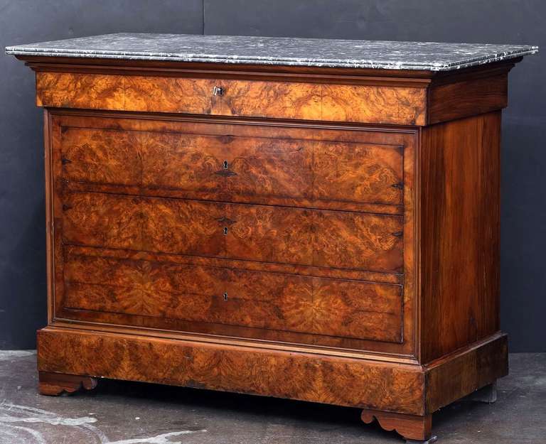A handsome French Louis Philippe chest or commode of burr walnut with a figured marble top. Featuring four fitted long drawers (with key) and set upon scrolled bracket feet.