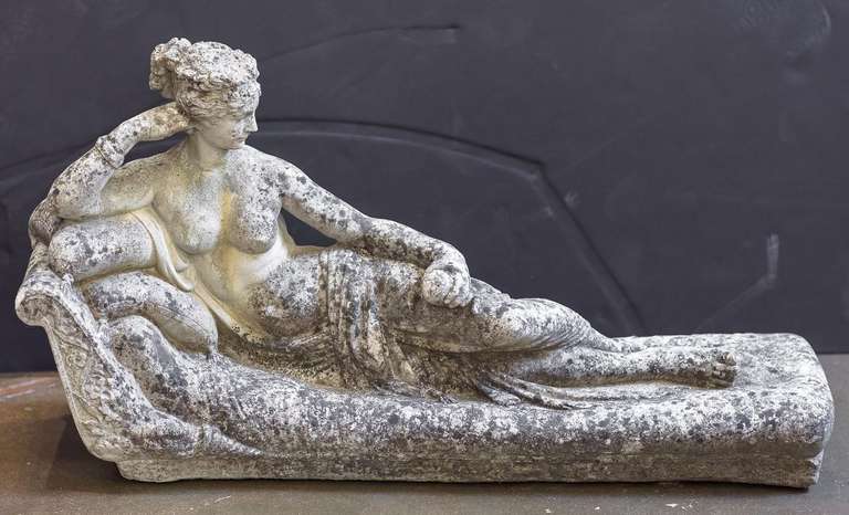 A lovely English garden stone ornamental figurine of a reclining classical lady or odalisque on a cushioned divan.