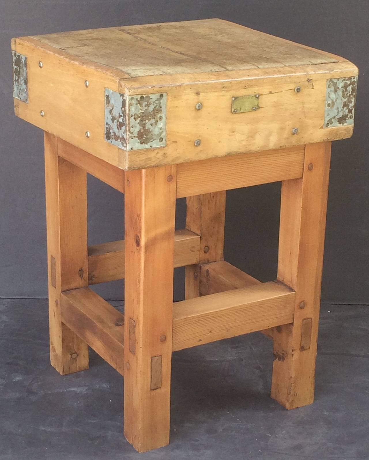 A handsome two-tiered French butcher's chopping block or table featuring a large, rectangular sloping block or slab of iron-bound wood set upon a bottom tier four-legged, paneled support stand of pine.

With brass label to front. Ships in two
