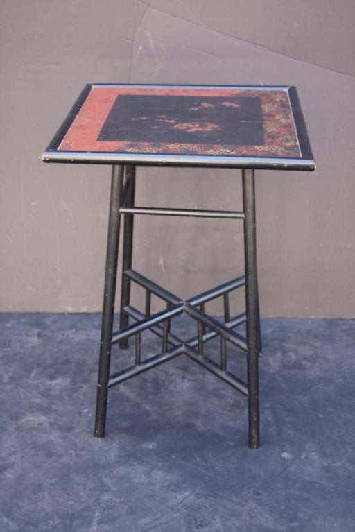 A handsome side or occasional table from the Arts & Crafts era in England, featuring a square japan-lacquered top with a chinoiserie design, framed in black lacquer, over a fretwork stretcher support, also in black or ebonized lacquer.

Perfect as