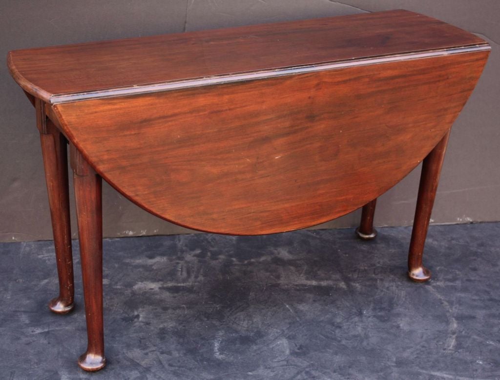 A handsome English drop-leaf table of fine Cuban mahogany from the George II period, featuring nicely-crafted demi-lune sides that fold up onto retractable cabriole legs to make a round or circular surface for dining or serving. Set upon pad