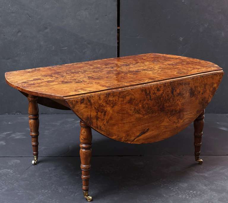 A handsome early 19th century French drop-leaf circular table of solid burr elm featuring a large round top (opens to 60
