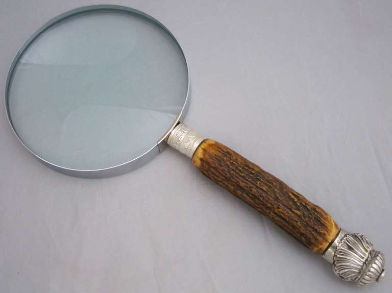 A large English hand magnifier or table top and desk magnifying glass featuring a large round looking glass mounted to a horn handle and capped with a silver foliate design.

Marked Hilkinson.

We have a selection of magnifiers in various styles