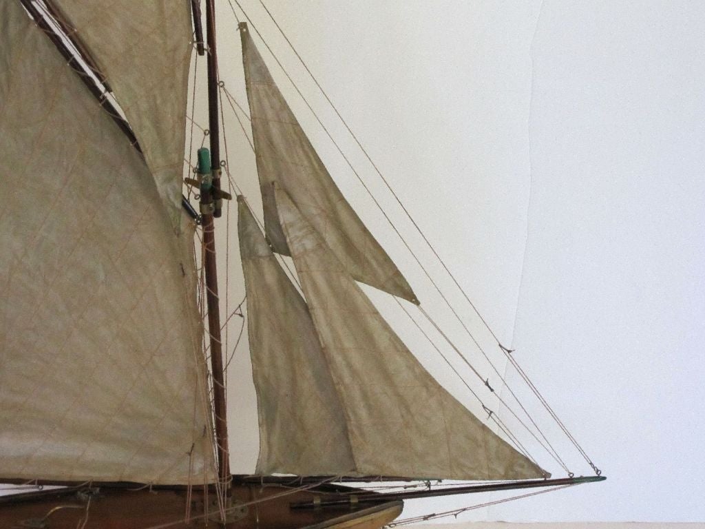 A handsome English pond yacht, handcrafted from wood and brass and featuring vintage cloth sails and fittings. <br />
Displayed on a separate, custom-fitted stand. <br />
<br />
An excellent gift for the nautical antiques collector.<br />
A