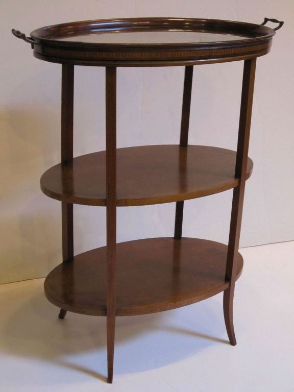 A fine English three-tiered étagère or tray table (serving or drinks table) with a removable glass and wood serving tray on the top tier.
Featuring a sophisticated design of three oval tiers attached to tapered legs.

Each tier with a band of inlaid