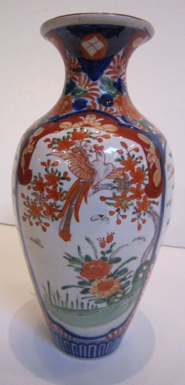 A decorative Imari vase from late 19th century Japan, featuring a design of birds and flowers around the circumference, with a cartouche of a lady in a kimono under an arbor.