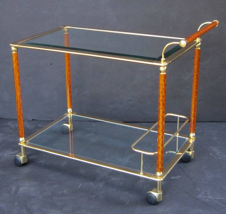 A French rolling drinks cart or serving trolley (bar cart) of gilt brass with faux tortoise accents and two glass tiers by Lancel.
Lancel is the name of a house of leather goods founded in Paris in 1876 by Angèle Lancel. Besides fine leather items,