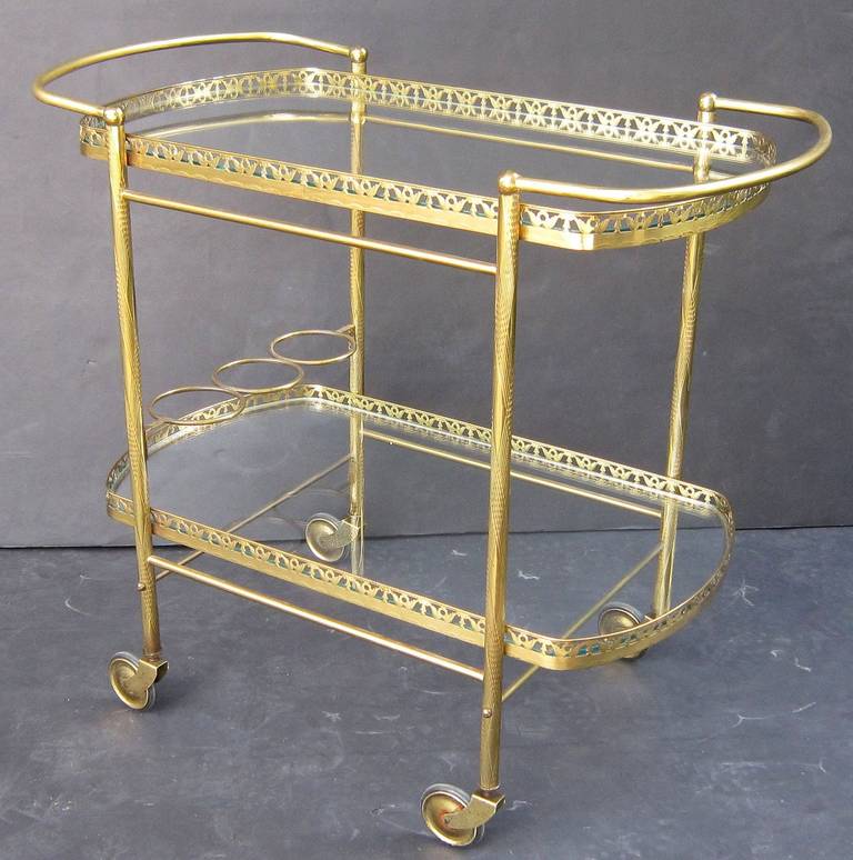 A vintage French oval drinks cart or serving trolley (bar cart) of brass and glass with pierced galleries and bottle holder, on rolling caster wheels. 

Perfect for use as a side or end table.