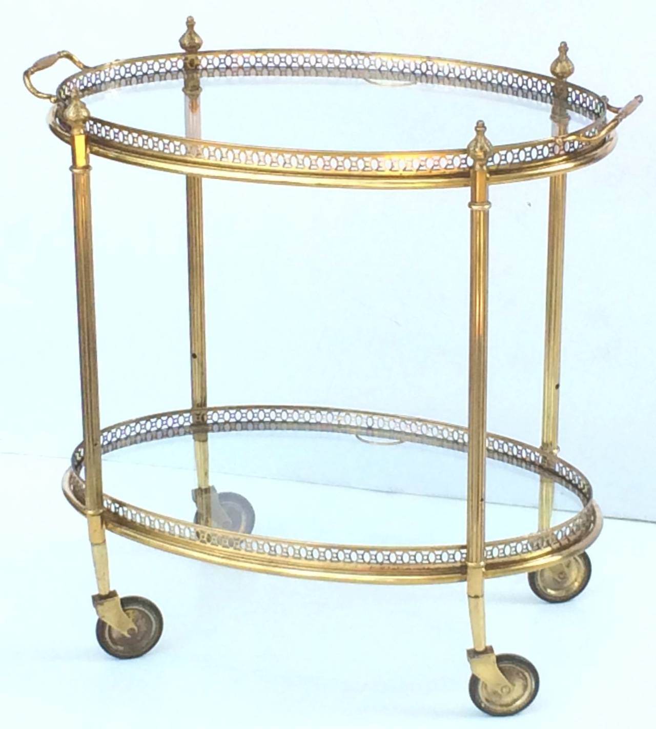 A vintage French oval bar cart or cocktail trolley of brass and glass with pierced galleries, removable top and bottom trays, on rolling caster wheels. 

Perfect for use as a side or end table or for serving.