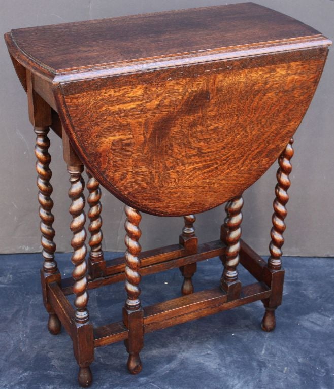 A classic English drop-leaf gateleg table of oak, featuring a moulded top with drop-down sides, over a stretcher of six barley-twist supports.<br />
<br />
Dimensions: H 29