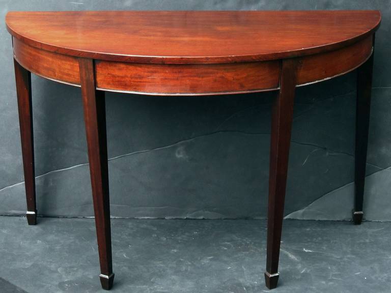 A handsome pair of English demilune (or half moon) console tables of mahogany, each featuring a moulded top on four tapering legs.

A great pair for an entry way or dining room, perfect for use as bedside tables.

Priced as a pair - $6950 the