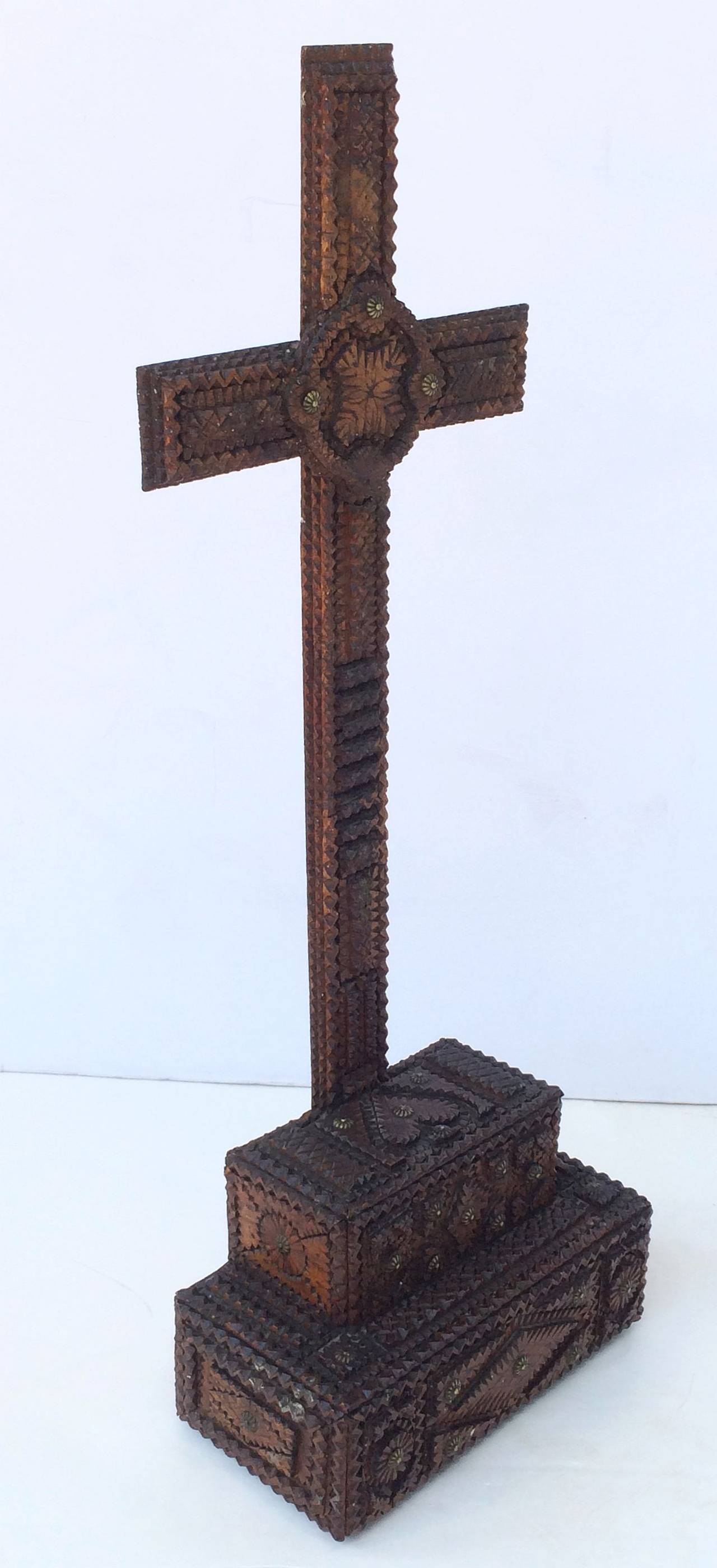 A handsome large Tramp Art crucifix of wood with brass embellishments featuring a cross mounted to a graduated box form for table display.
The whole adorned with ornamental relief designs and a heart on the top of the box mounting.

Dimensions: 