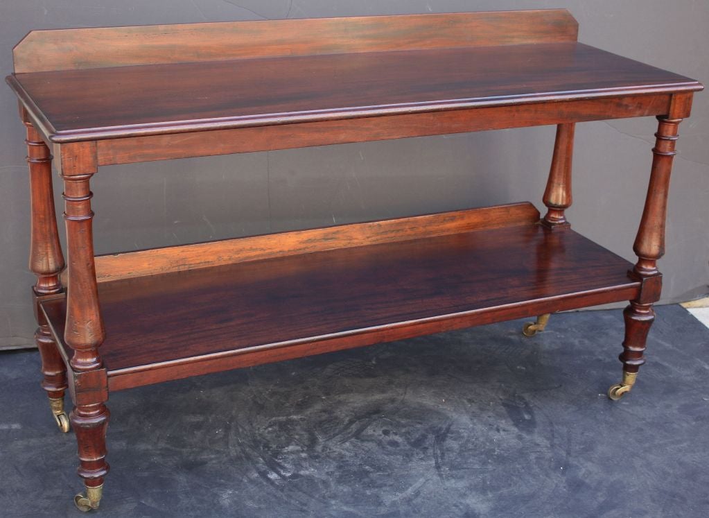 A handsome Scottish two-tiered trolley server (or dumb waiter) of mahogany featuring two moulded tiers with gallery backs supported by four baluster-turned columns, on rolling brass casters.

Such servers (often referred to as trolley servers,