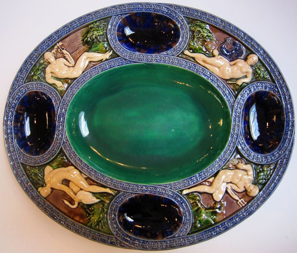 A beautiful Majolica oval platter in a Romanesque style by the celebrated pottery firm, Minton. Featuring four cartouches from Classical mythology - Mercury, Juno, Leda and the Swan, and Neptune - modelled after Palissy's early Greco-Roman styled