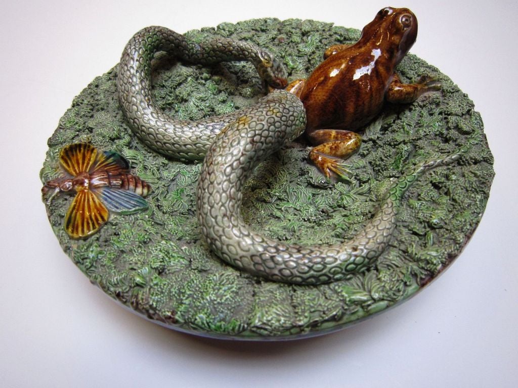 A wonderful 19th c. Majolica Palissy charger featuring a large snake, a frog, and a moth or butterfly - all in high relief on a green mossy ground (bocage). A mottled, tortoise-coloured underside with impressed maker's mark.