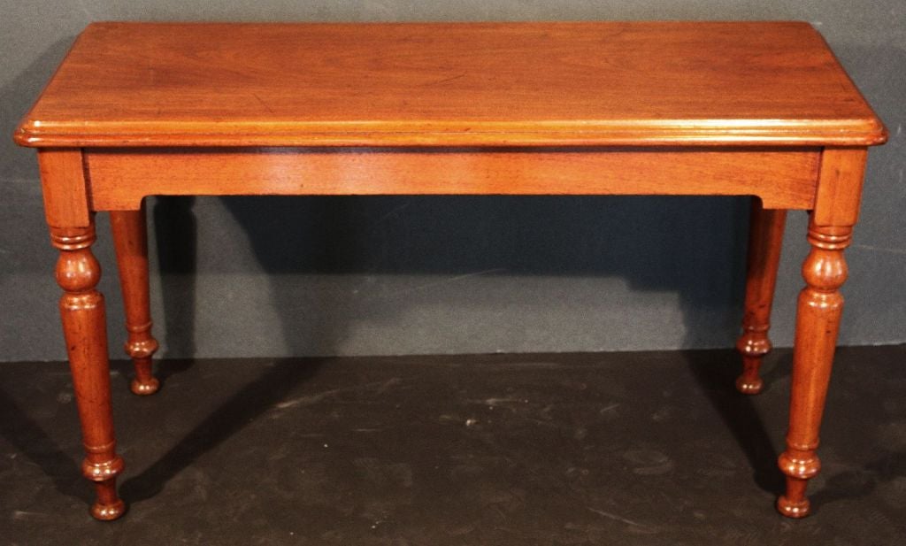 A handsome English console or sofa table of mahogany, from the late 19th century, featuring a rectangular moulded top over a frieze of four turned baluster legs.