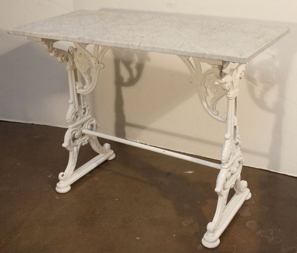 An English bistro or console pub table featuring a rectangular figured marble top set upon a base of cast iron. The base with an ornamental design of acanthus leaves, florets, and fanciful scrollwork.

Perfect for a garden room or conservatory!