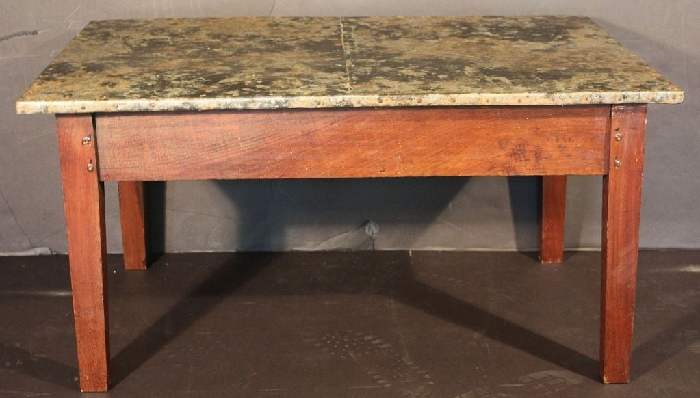 An authentic French farm table, modified for use as a cocktail or low table, featuring an added top of riveted zinc with a unique mottled, weathered industrial design.

Perfect for use as a coffee table.