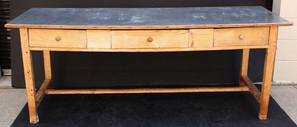 An English table or console of pine featuring a zinc top over a frieze of three drawers and stretcher base. 

Perfect for a country home or ranch house.