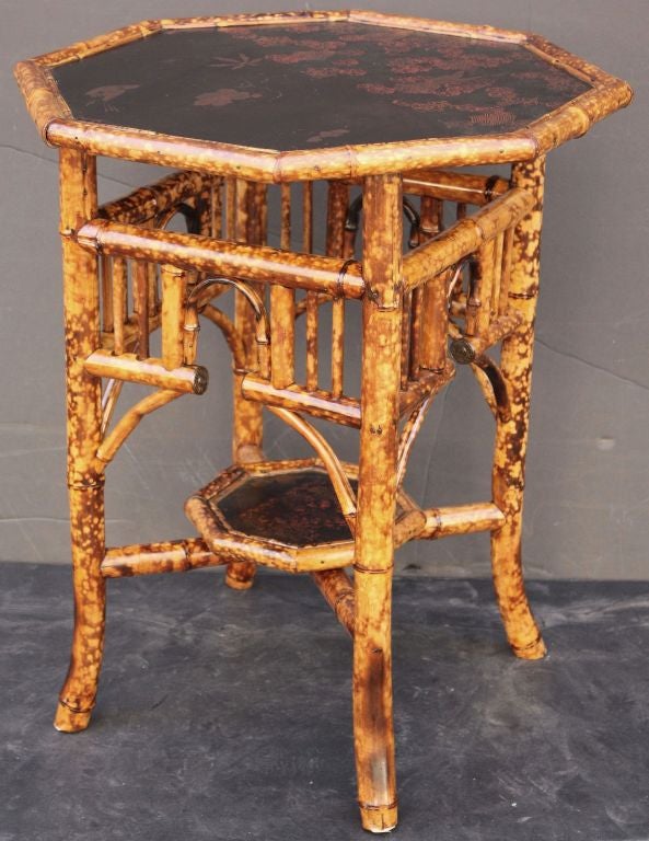 An English bamboo table featuring an octagonal lacquered top of framed bamboo over an undertier of bamboo with Arts and Crafts era style.