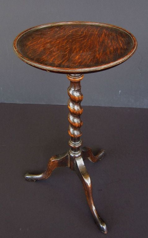 An English wine table of oak from the Edwardian-era, featuring a raised pie-crust edge around the circumference of the round top, set upon a turned barley twist pedestal with tripod base. Set upon lovely pad feet. 
An excellent choice as a side