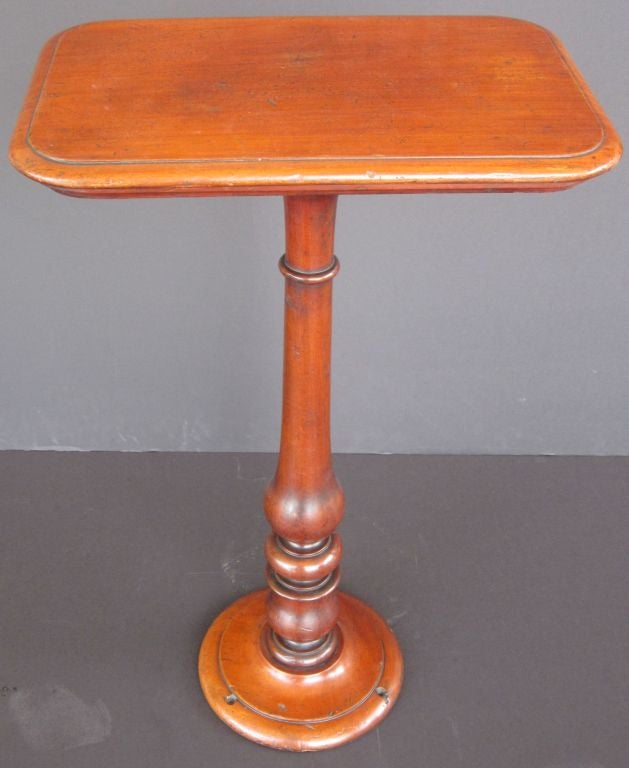 An English ship's table or occasional table of mahogany featuring a moulded rectangular top attached to a turned column and base. 
The circular base featuring screw holes allowing for floor mounting.

A great find for a collector of maritime of