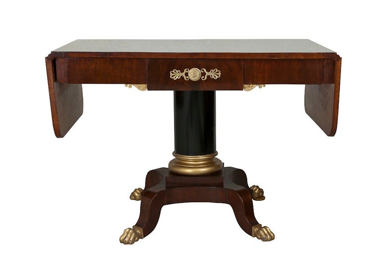 A beautiful Karl Johan table made during the period 1810-1830. Made in mahogany with gilded lion feet and column base. Drawer in frieze is decorated with a gilt bronze lion head surrounded by palm leaves - characteristic for the period. Signed SEST