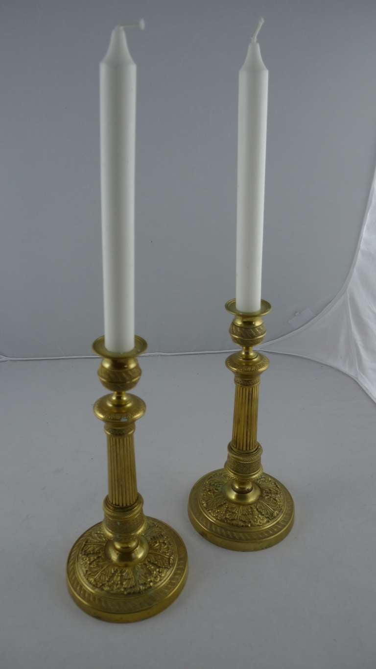 A pair of candlesticks made during the empire period 1810-1830 in France. Urn shaped candleholders and a rounded channeled body standing on a round foot decorated with flowers.  