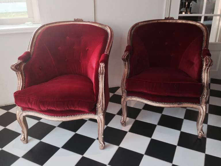 A pair of Italian bergeres in a distressed gilt wood finish with beautiful dark red coming through. Made in a Rococo style. Newly upholstered with a loose cushion.