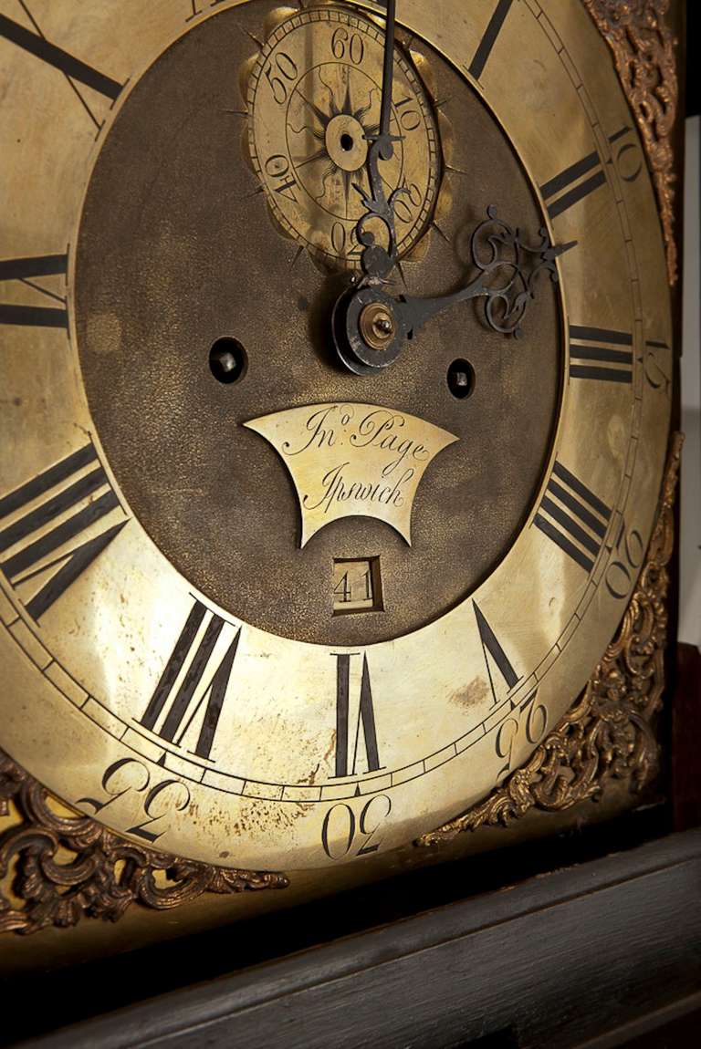A tall grandfathers clock with a face made of polished brass decorated with roman numerals. Hands in dark patinated brass and a date window (image 3). Case in black lacquer with gold-leaf paintings of landscapes, pagodas and weeping willows (image