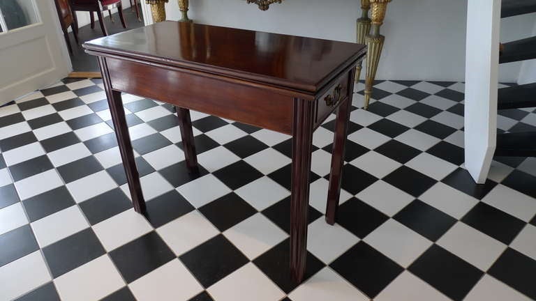 Table Game English 18th Century Mahogany England. An English game table from the end of 18th Century. Squared and channeled legs with two folding out for when the table is open to its double size. Open: 33 in.  Drawers on each end.