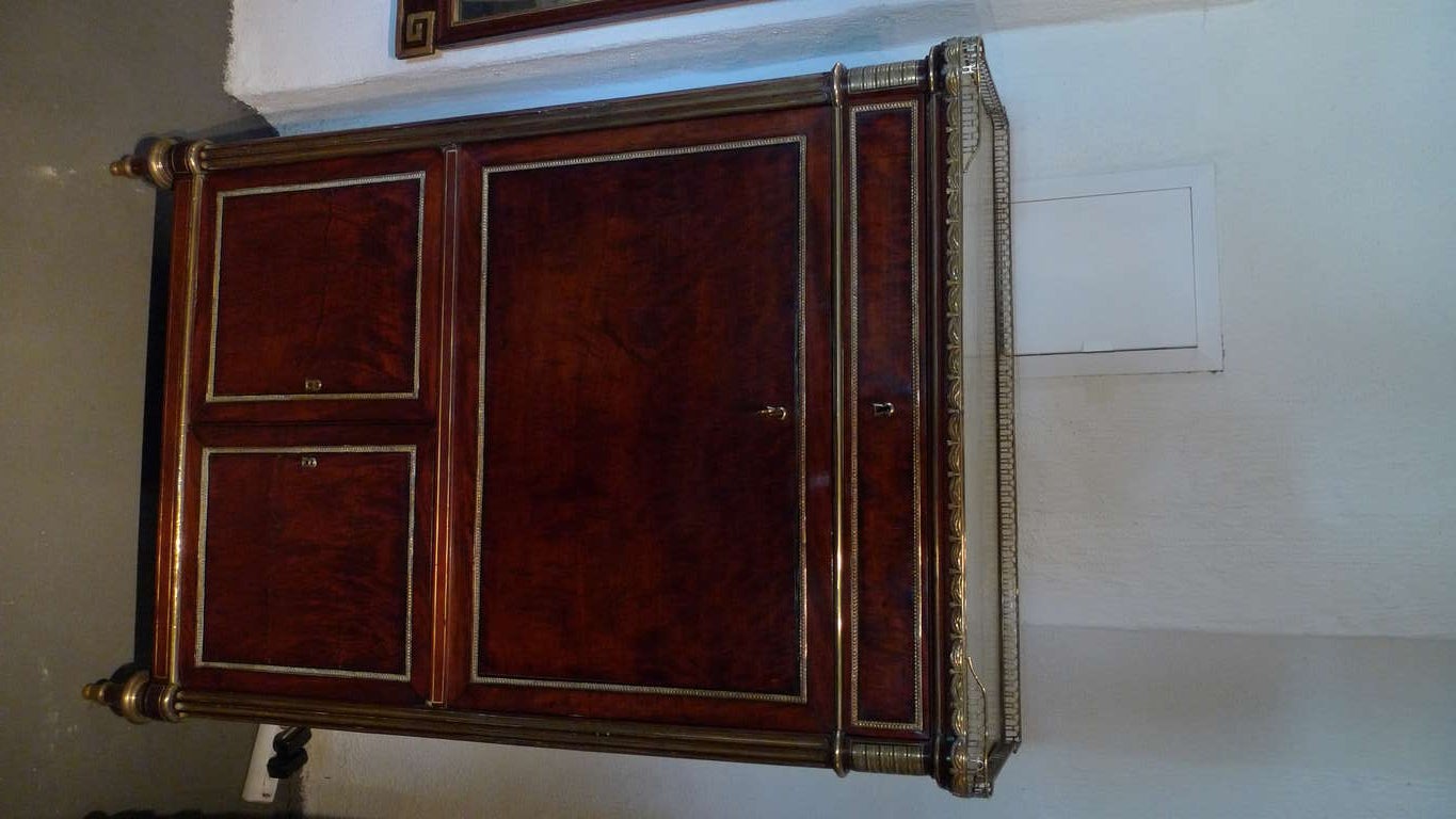 A French secretary made in mahogany with gilt bronze details. Gilt bronze details around the cabinet doors, brass filled channels on rounded corners and a laced trim in gilt bronze along the marble top. Writing desk with drawer interior in side.