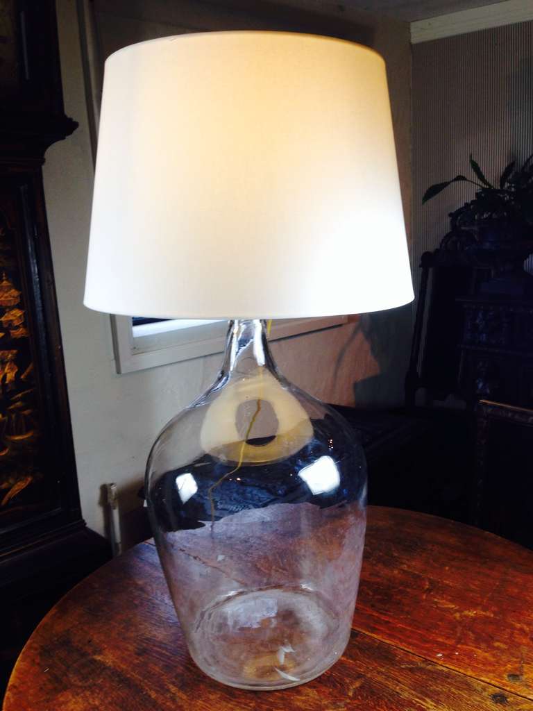 Large glass table lamp made from a 19th C French wine container in clear glass.