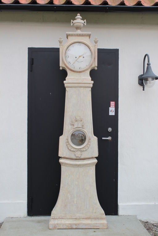 A tall Swedish Gustavian floor clock with carved decorations and original paint