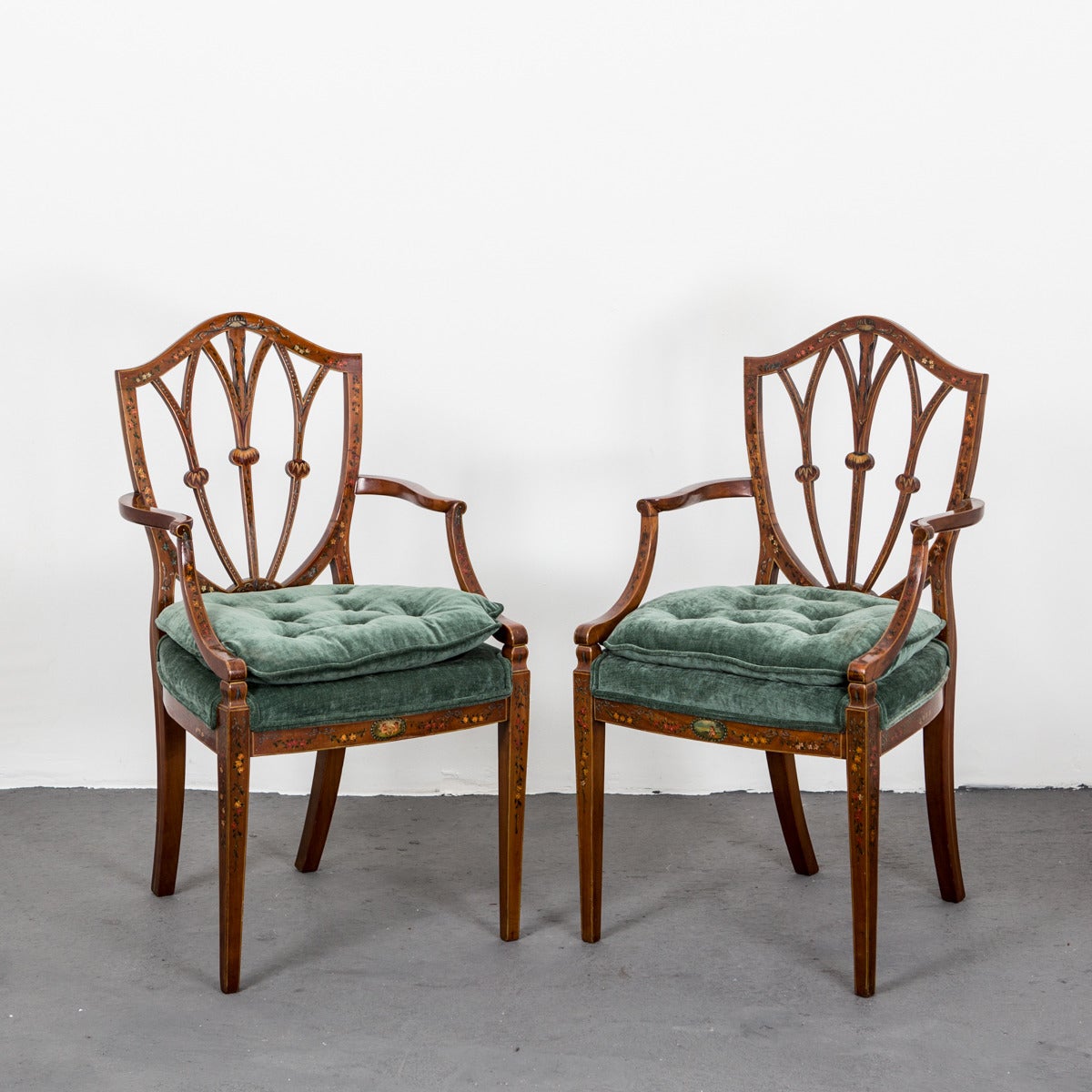 A pair of English armchairs in mahogany with painted colorful details made during the 18th Century Hepplewhite type. Shield shaped back and back curved armrests. Previously owned by an opera singer from Manhattan, New York. Upholstery contemporary.
