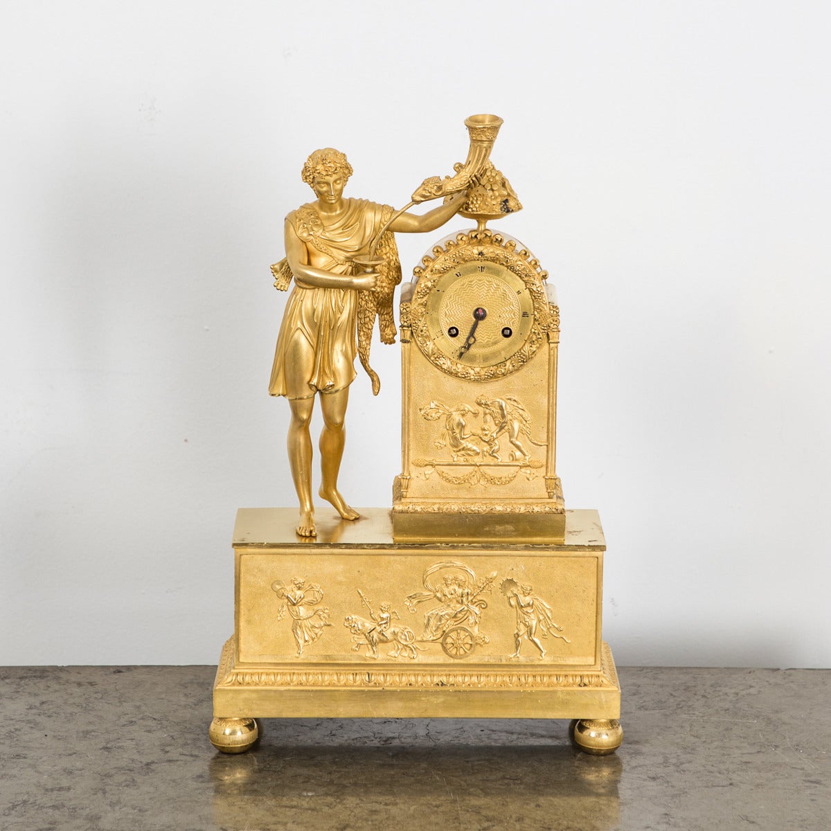 Clock Mantle Gilt Bronze Neoclassical Empire French 19th Century France. A French mantle in gilt bronze decorated with neoclassical symbols such as Roman man dressed in a Toga carrying a horn - the symbol for wealth.