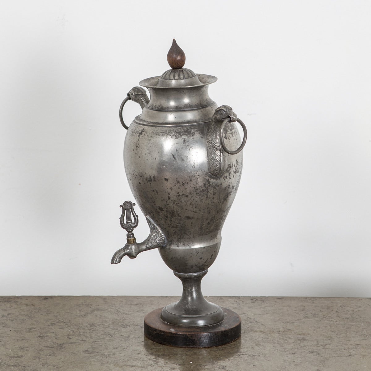A hot water container in pewter made in Sweden during the first part of the 18th Century and the Empire period. Wooden details such as lid finial and base.