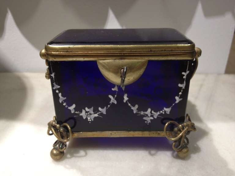 A gorgeous box made of blue glass beautifully decorated with white details. Frame of brass. original lock and key. Made during 19th Century Russian Empire period. Small lockable boxes like these were made to keep the expensive sugar.