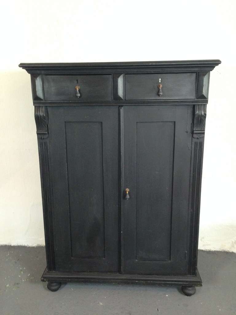 Swedish cupboard made during end of 19th century. Later finish in matt black paint. Standing on ball feet. Two drawers and shelving interior.