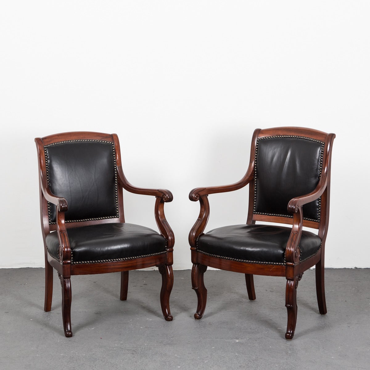 Armchairs pair French Directoire mahogany black leather France. A pair of French Directoire armchairs made in France during 1790-1810. Frame made in a beautifully patinated mahogany. Seat and back upholstered in a soft black leather.