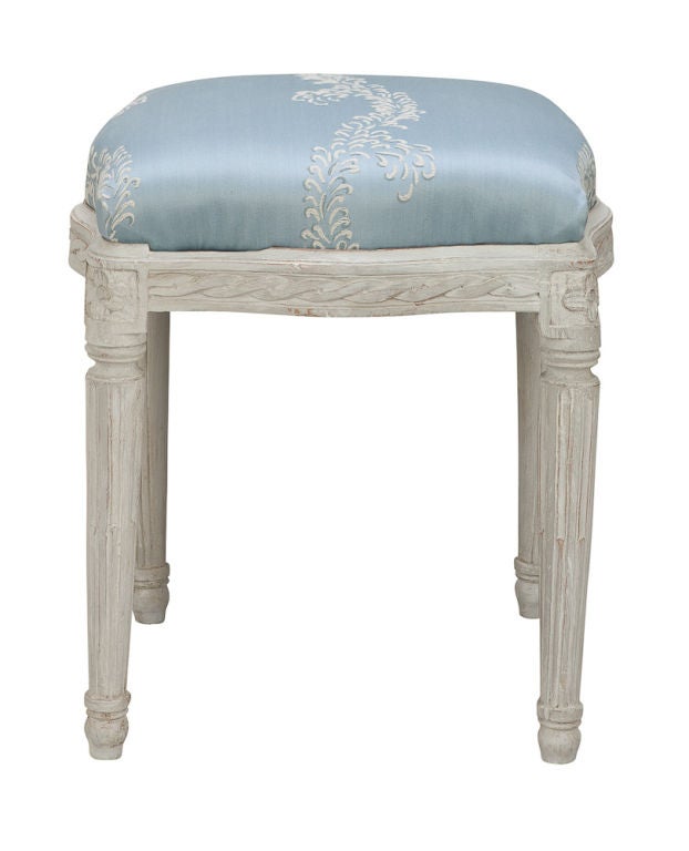 A single Gustavian stool with a curved frieze decorated with a braided band, the corners with carved flowers and half filled channels on the fluted legs.