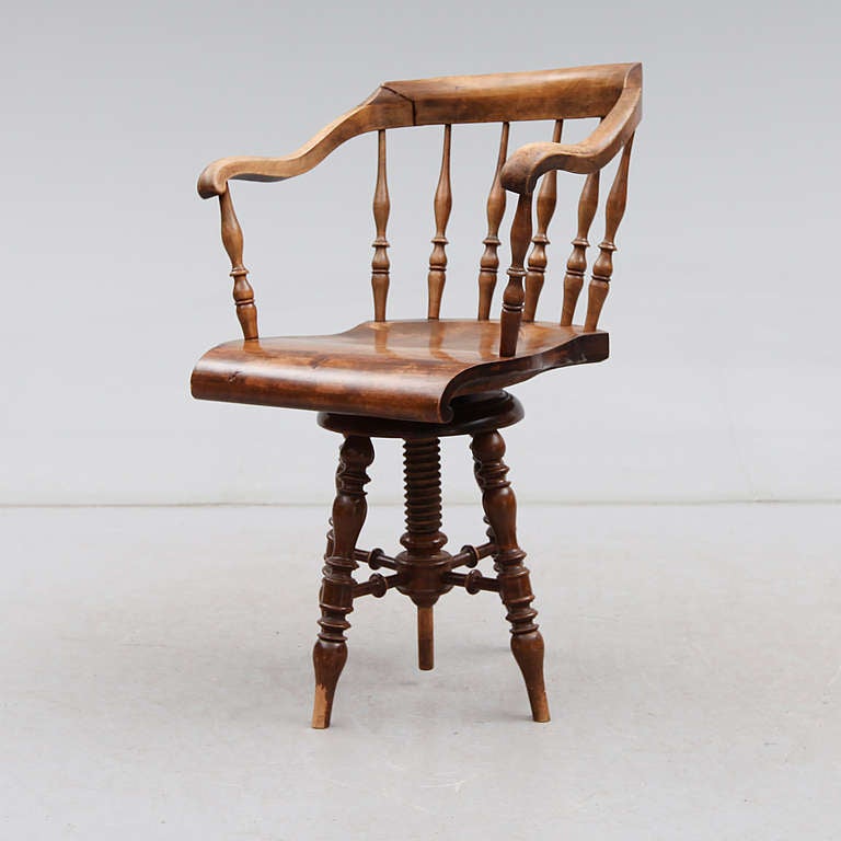 A desk chair made in oak with back of spindles. Adjustable seat height. Made in Sweden during the early part of 20th century.